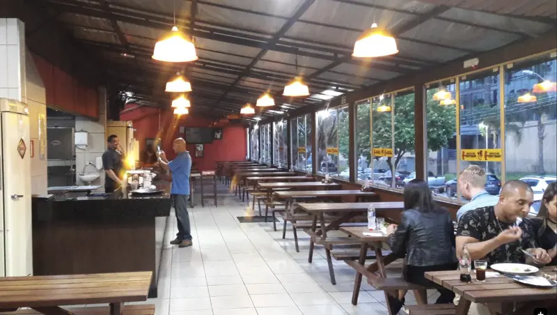 Salão do Costelão Curitibano com mesas de madeira e janelas para a rua